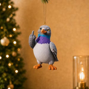 Könnte beinhalten: Ein hängendes Ornament in Form einer grauen Taube mit orangefarbenem Schnabel und Füßen sowie einem violett-blauen Halsfleck. Die Taube hat einen mürrischen Gesichtsausdruck und hebt ihren rechten Flügel in einer obszönen Geste, aufgehängt an einer goldenen Schnur.