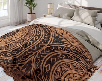 May include: A brown and black patterned blanket with a tribal design is draped over a bed. The blanket features geometric shapes and curved lines. The bed has white and grey bedding, and the room has a plant and a window.
