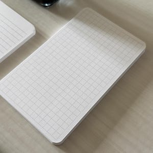 A focus view of a set of index card-sized note cards on a white table. The card on the left has a line with mini vertical dots layout. The stack of cards on the right has a graph layout. The graph card is focused in to show the graph lines.