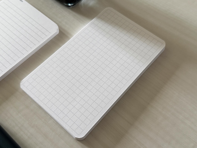 A focus view of a set of index card-sized note cards on a white table. The card on the left has a line with mini vertical dots layout. The stack of cards on the right has a graph layout. The graph card is focused in to show the graph lines.