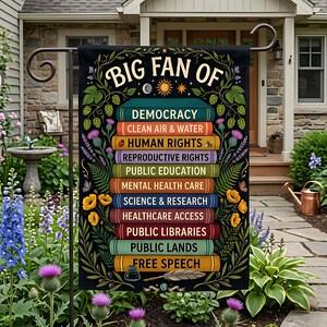 Könnte beinhalten: Schwarze Gartenflagge mit dem Text "BIG FAN OF" und einer Liste von Werten, darunter "DEMOCRACY", "CLEAN AIR & WATER" und "HUMAN RIGHTS". Die Flagge ist mit floralen und botanischen Elementen verziert.