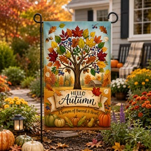 Könnte beinhalten: Eine rechteckige Gartenflagge mit einem zentralen Baum mit bunten Herbstblättern, Eicheln und Beeren. Unter dem Baum zeigt ein Banner den Text Hello Autumn A Season of Harvest & Heart, mit Kürbissen und Maiskolben am unteren Rand.