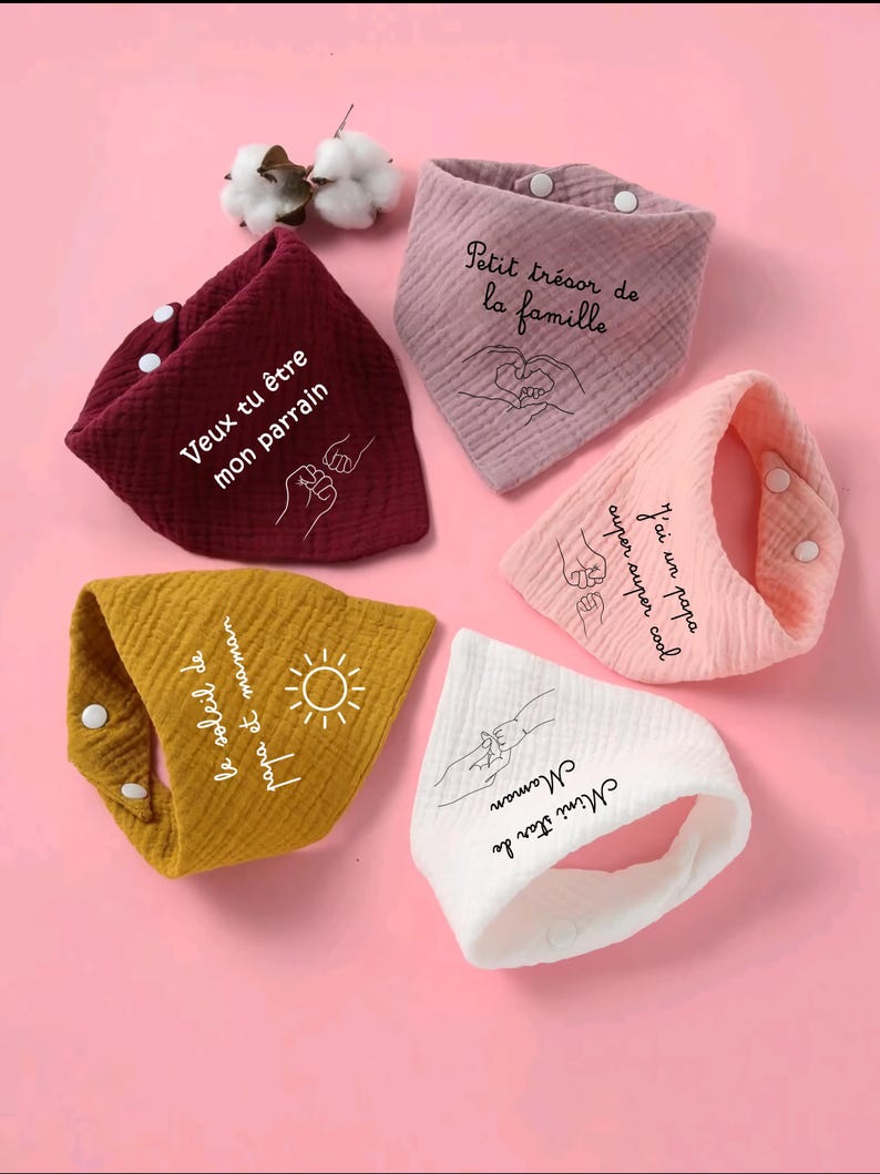 K&ouml;nnte beinhalten: F&uuml;nf Baby-L&auml;tzchen in verschiedenen Farben, darunter Burgunderrot, Rosa, Gelb und Wei&szlig;. Jedes L&auml;tzchen hat einen Druckknopfverschluss und ein einzigartiges Design mit Text und Illustrationen. Die L&auml;tzchen sind aus weichem, strukturiertem Stoff.