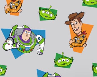 May include: A repeating pattern featuring cartoon characters Buzz Lightyear, Woody, and Little Green Men from the Toy Story franchise. The characters are set against a gray background with colorful geometric shapes.