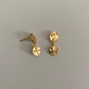 May include: A pair of gold-toned dangle earrings with two round, textured discs on each earring.