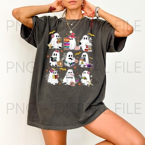 Könnte beinhalten: Ein anthrazitfarbenes Kurzarm-T-Shirt mit einem Grafikdruck von neun weißen Geistern, die Bücher lesen. Die Geister sind mit verschiedenen Accessoires wie Hüten, Brillen und Blumen dargestellt und von kleinen orangefarbenen Fledermäusen und Spinnennetzen umgeben.