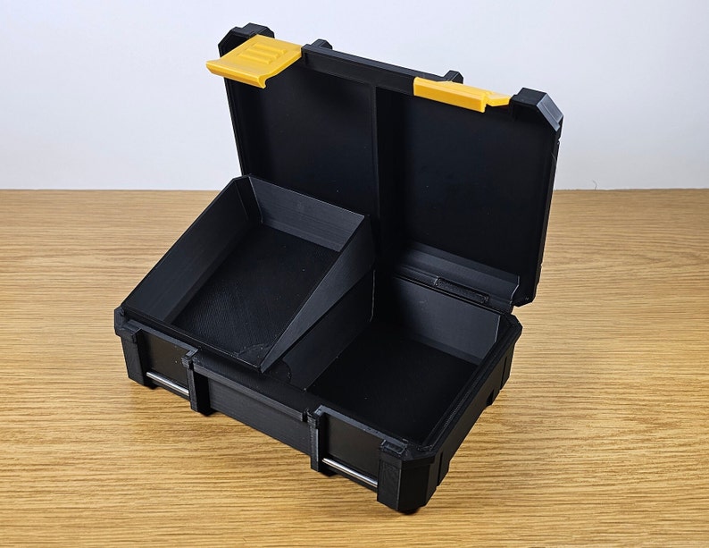 May include: A black plastic storage box with a yellow latch. The box has a removable divider and is open to reveal the interior.