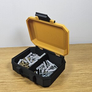 May include: A black and yellow plastic storage box with two compartments filled with screws and nails.