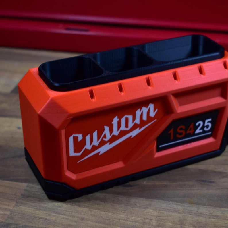 May include: An orange and black custom-made organizer with three compartments. The word "Custom" is printed in white, along with the numbers "1S425". The organizer is made of a durable material and is designed for tools or small items.