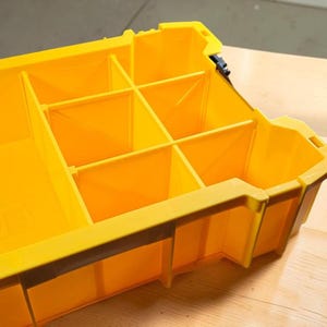 May include: A bright yellow plastic storage organizer tray featuring multiple fixed compartments of varying sizes. The rectangular container has molded walls and a sturdy rim, designed with internal dividers to create distinct sections for sorting items.