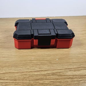 May include: A red and black plastic storage case with a hinged lid. The case is empty.
