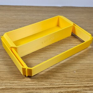 Op de afbeelding: Een gele plastic opbergdoos met een deksel. De doos bestaat uit twee delen die in elkaar passen. Het deksel heeft een klein label met de tekst "LAGO"