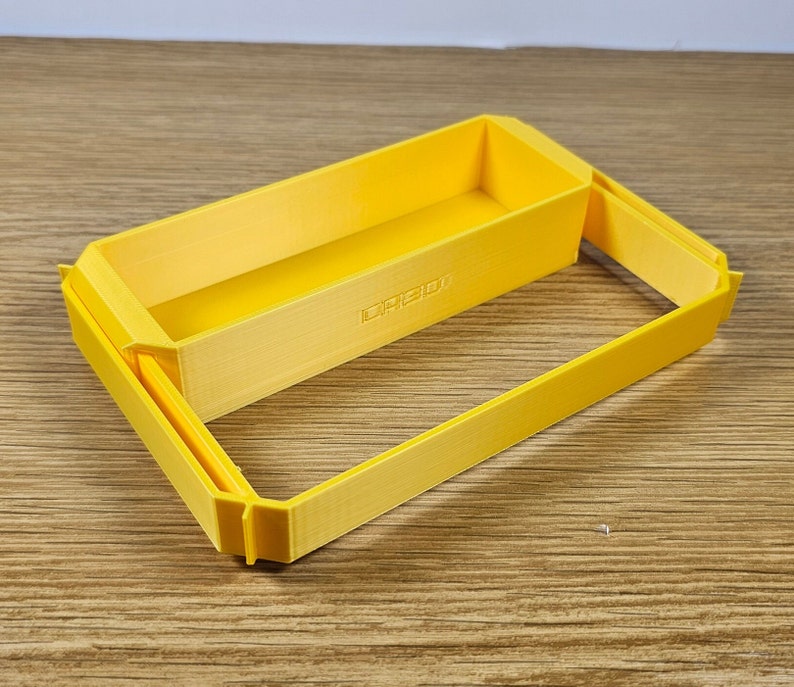Op de afbeelding: Een gele plastic opbergdoos met een deksel. De doos bestaat uit twee delen die in elkaar passen. Het deksel heeft een klein label met de tekst "LAGO"