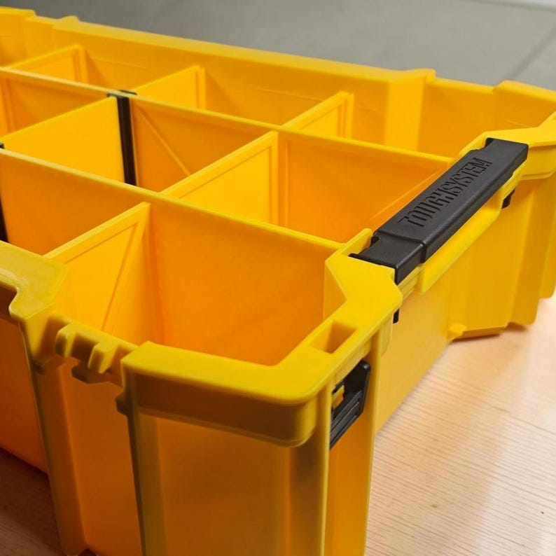 May include: A bright yellow plastic storage organizer tray featuring multiple square compartments for sorting small items. The unit includes a black handle on the side with the text TOUGHSYSTEM embossed in black lettering on the handle surface.