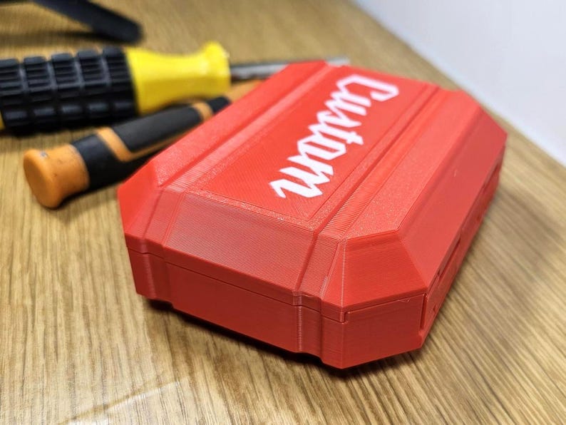 May include: A red plastic case with the word "Guardian" printed in white on the top. The case is closed and has a textured surface.