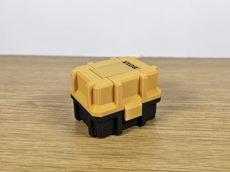 May include: A small, yellow and black plastic box with the word "BOXX" printed on the top.