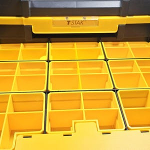 May include: A yellow and black STAK organiser with multiple compartments. The organiser has a clear plastic label holder and is designed for storing small parts or tools. The compartments are various sizes and shapes.
