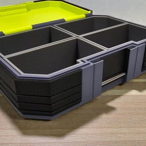 May include: A multi-compartment storage box with a hinged lid. The box is primarily gray and black, with a bright yellow interior and dividers. The box appears to be made of plastic and is designed for organizing small items.
