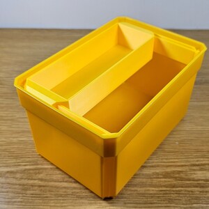 Op de afbeelding: Een felgele plastic opbergdoos met een verdeler. De doos heeft een rechthoekige vorm en is gemaakt van duurzaam materiaal.