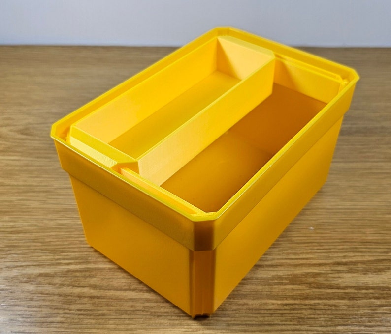 Op de afbeelding: Een felgele plastic opbergdoos met een verdeler. De doos heeft een rechthoekige vorm en is gemaakt van duurzaam materiaal.