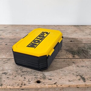 May include: A yellow and black rectangular box with the word "CUSTOM" printed on the top in black. The box is sitting on a weathered wooden surface.