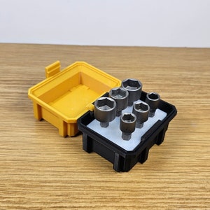 May include: A black plastic case with a yellow lid holds a set of six silver socket wrenches.
