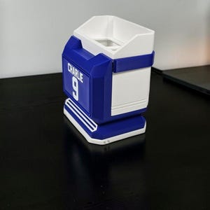 May include: A blue and white container with the name "Charlie" and the number "9" on the side. The container has a rectangular shape with a white interior and a blue exterior with a white trim.