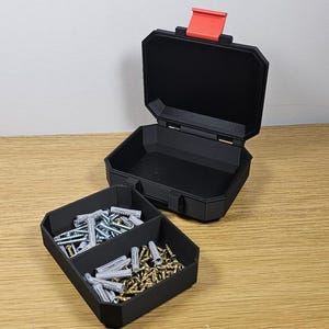 May include: Black, open toolbox with a red latch, and a separate tray with compartments. The tray contains various screws and wall anchors. The toolbox is on a wooden surface.