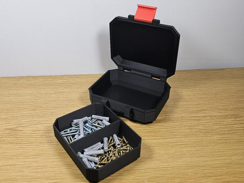 May include: Black, open toolbox with a red latch, and a separate tray with compartments. The tray contains various screws and wall anchors. The toolbox is on a wooden surface.