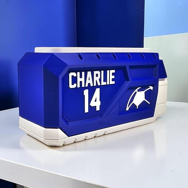 May include: A rectangular blue and white storage container featuring the name CHARLIE and the number 14 in white lettering on the front. The design includes a white graphic icon of a stylized shield or emblem on the right side of the blue panel.