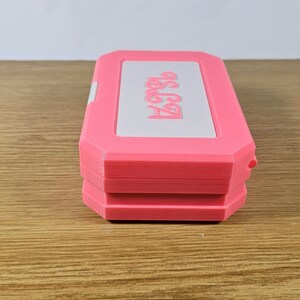 May include: A pink and white plastic case with the text "Get Started" printed on the top. The case is closed and has a textured surface.