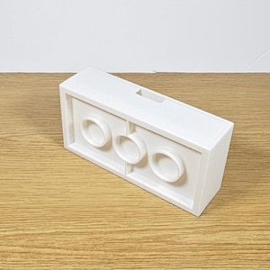 May include: White plastic brick with three round holes. The brick is designed to be used with other bricks.