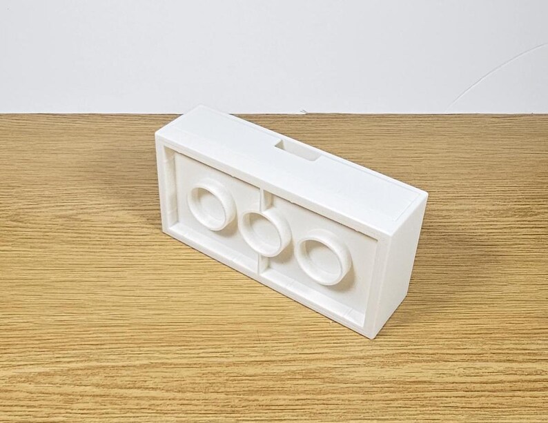 May include: White plastic brick with three round holes. The brick is designed to be used with other bricks.