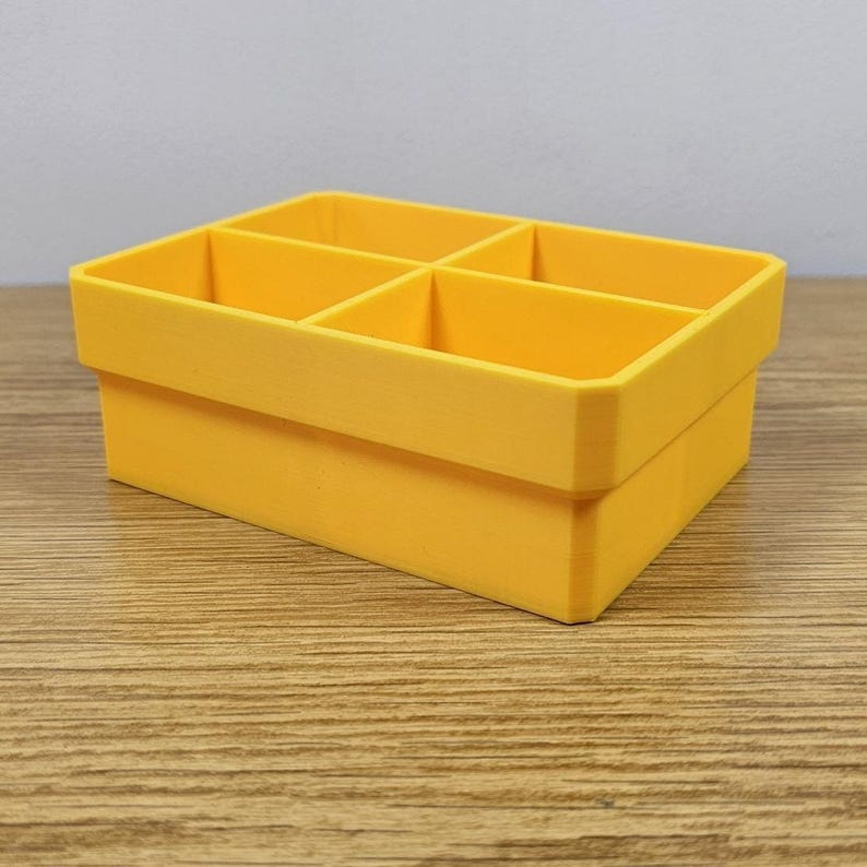 May include: A bright yellow, rectangular organizer with six compartments. The organizer is made of a solid material and has a clean, modern design. The compartments are evenly sized and ready to hold small items.
