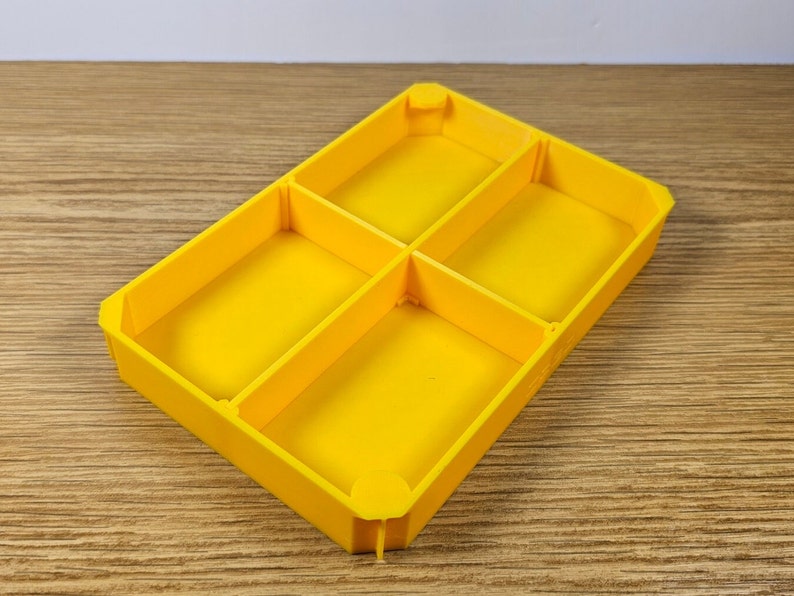 May include: A yellow plastic tray with four compartments. The tray is empty.