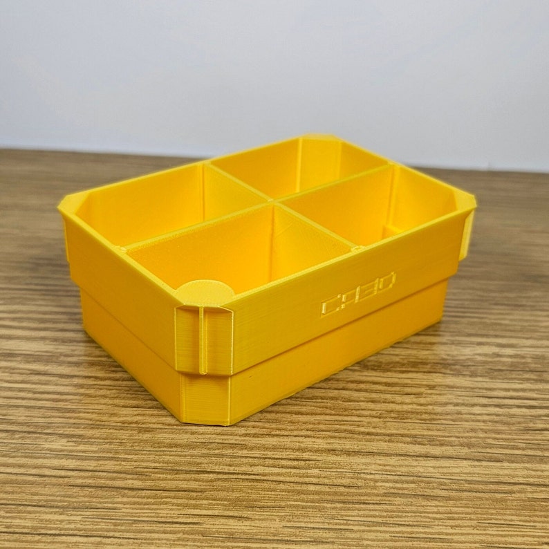 May include: A yellow plastic storage box with four compartments. The box has the word "CREO" printed on the bottom.