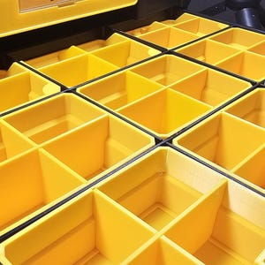 May include: A yellow and black organizer with multiple compartments. The compartments are rectangular and arranged in rows and columns. The organizer is designed to store small items and tools. The color scheme is bright and functional.
