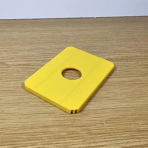 Pode incluir: Uma bandeja de gelo de pl&aacute;stico amarelo com um furo circular no centro. A bandeja tem uma superf&iacute;cie texturizada.
