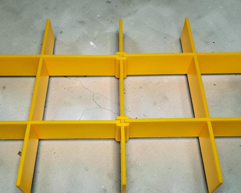 May include: A close-up of a bright yellow plastic grid structure. The grid is formed by intersecting rectangular bars, joined with interlocking components. The design creates a robust framework. The image focuses on the grid's construction and colour.