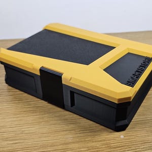 May include: A yellow and black plastic storage box with the word "SMARTSTORY" printed on the side.