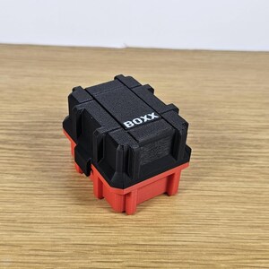 May include: A small black and red storage box with the word "BOXX" printed on the top.