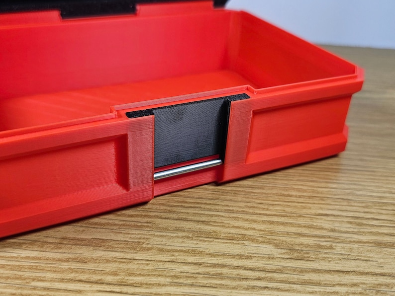 May include: Red plastic storage box with a black latch and a silver metal handle. The box is open and the inside is visible.