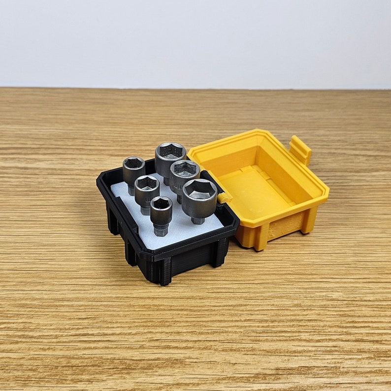 May include: A black plastic case with a yellow lid holds a set of seven silver socket wrenches.