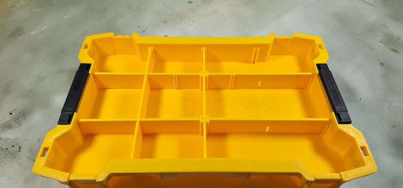 May include: Bright yellow plastic organizer with multiple compartments. Features black handles on each side. The organizer is designed for storing and organizing small items.