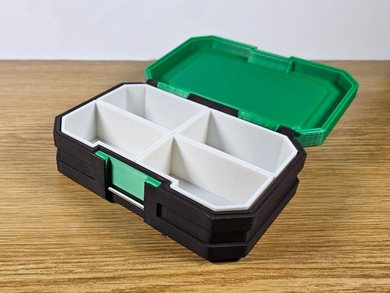May include: A black and green plastic storage box with four compartments. The lid is open and the compartments are empty.