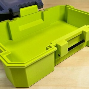 Peut inclure: Un conteneur de stockage en plastique vert citron de forme rectangulaire. Le conteneur a un couvercle et une poign&eacute;e noire. Le conteneur est pos&eacute; sur une surface en bois. Un autre conteneur est visible en arri&egrave;re-plan.
