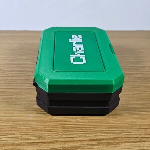May include: A green and black plastic storage box with the word "Charlie" printed in white on the top.
