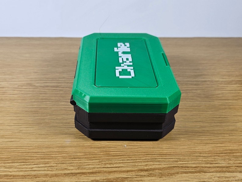 May include: A green and black plastic storage box with the word "Charlie" printed in white on the top.