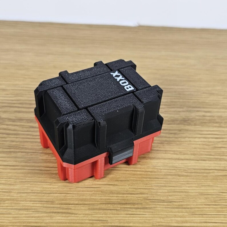 May include: A small black and red plastic storage box with the word "BOX" printed on the top.
