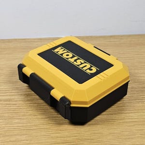 May include: A yellow and black plastic storage case with the word "CUSTOM" printed on the top.
